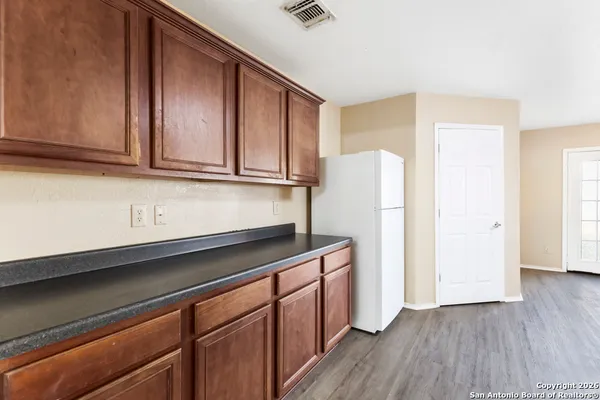 a kitchen with granite countertop wooden cabinets and a refrigerator