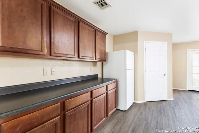 a kitchen with granite countertop wooden cabinets and a refrigerator