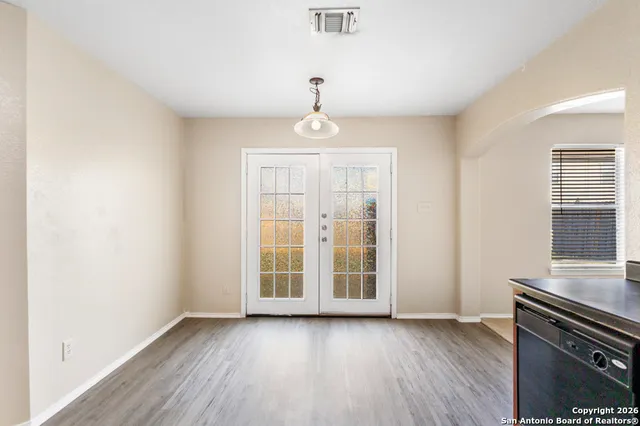 an empty room with wooden floor cabinet and windows