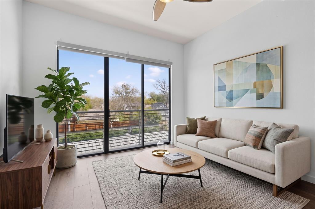Spacious living area featuring floor-to-ceiling windows, wood-finish flooring, and a modern ceiling fan