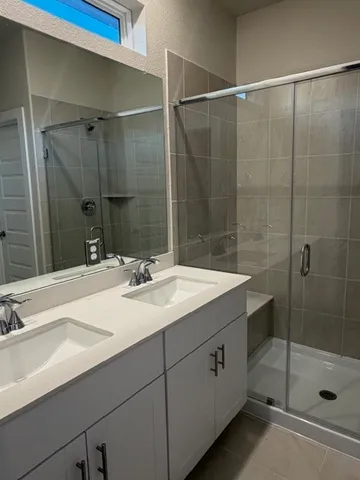 a bathroom with a double vanity sink mirror and shower