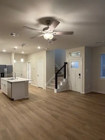 a view of an empty room with wooden floor and a ceiling fan