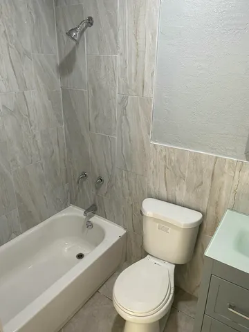 a white toilet sitting next to a bath tub
