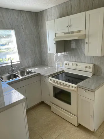 a kitchen with granite countertop white cabinets and white stainless steel appliances