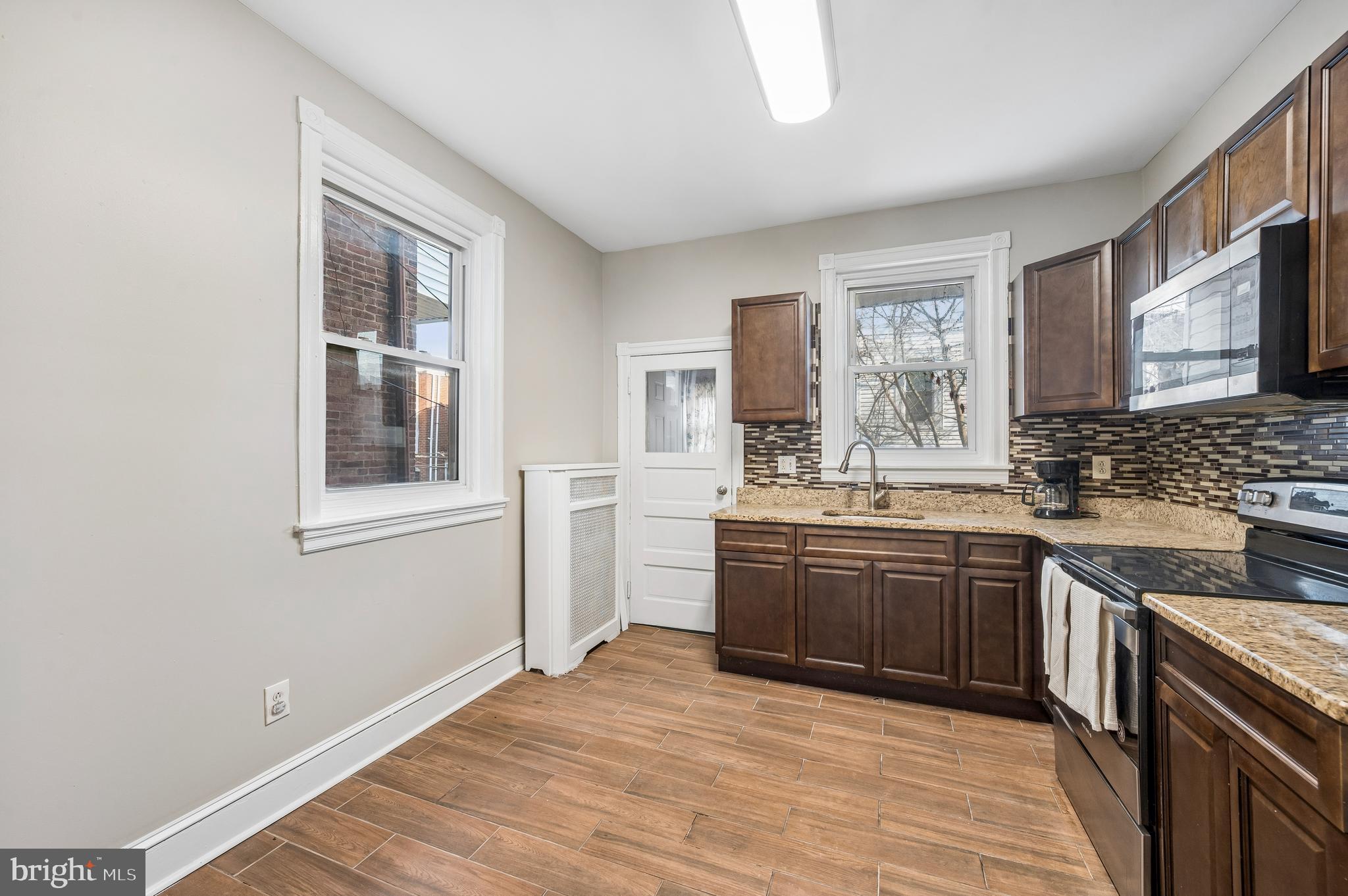 5428 Whitby Avenue Philadelphia, PA 19143 - Photo 8 of 15 a large kitchen with granite countertop a stove top oven a sink dishwasher a dining table and chairs with wooden floor