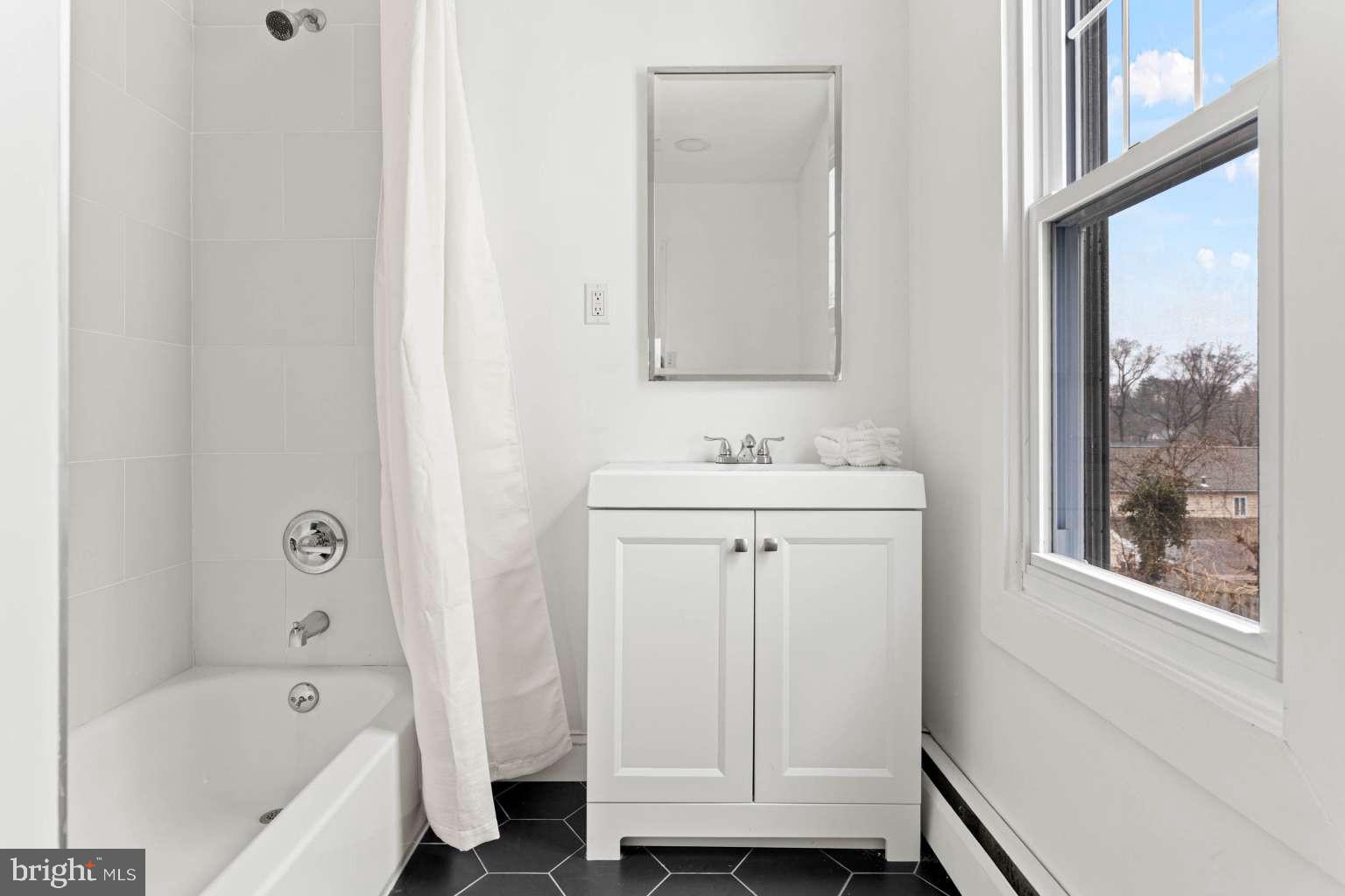 209 Willow Road Wallingford, PA 19086 - Photo 20 of 25 a bathroom with a sink a bath tub and a mirror