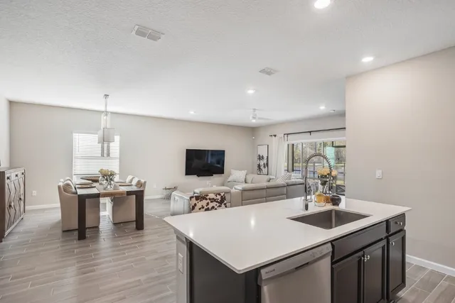 a kitchen with a sink dishwasher a dining table and chairs with wooden floor