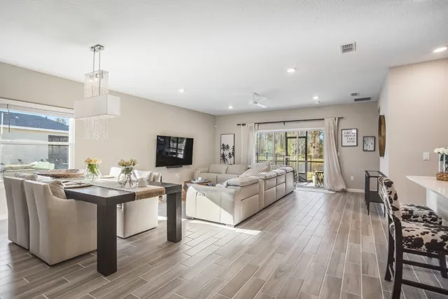 a living room with stainless steel appliances granite countertop furniture wooden floor and a view of kitchen