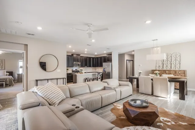 a living room with furniture kitchen view and a chandelier