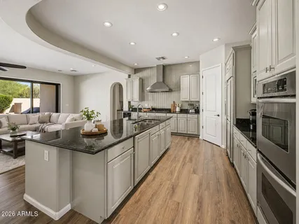 a large kitchen with stainless steel appliances granite countertop a lot of counter space and wooden floors