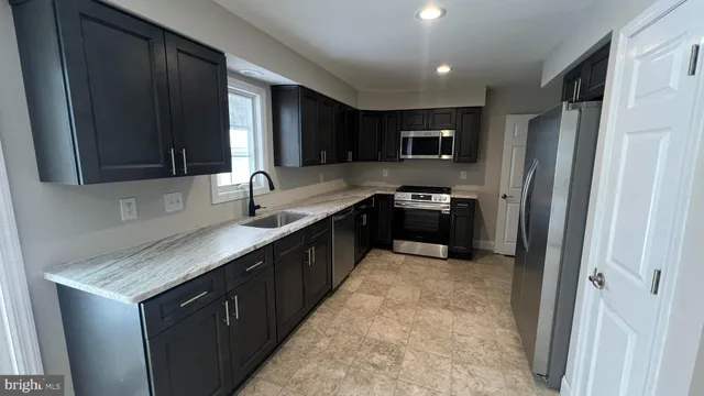 a kitchen with granite countertop stainless steel appliances a sink stove and refrigerator