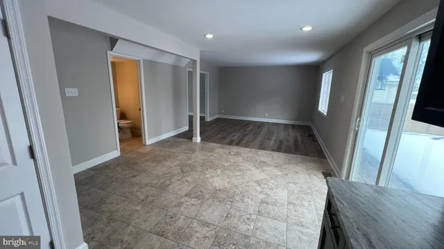 a view of an empty room with wooden floor and a bathroom