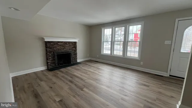an empty room with wooden floor fireplace and windows