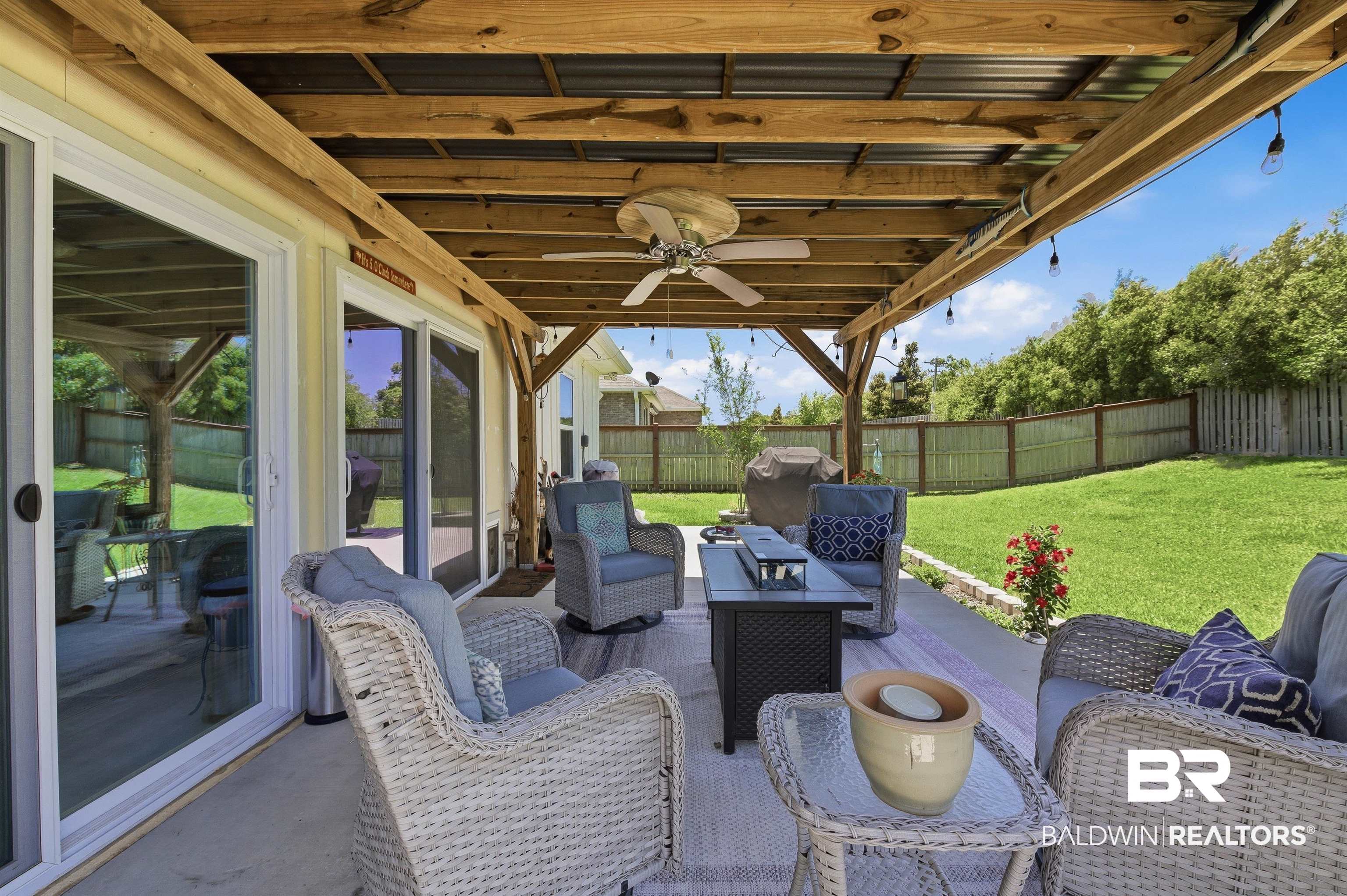 8735 Bronze Lane Foley, AL 36535 - Photo 40 of 58 Covered patio featuring a wood-beam ceiling with corrugated metal roofing, an installed ceiling fan, and string lighting