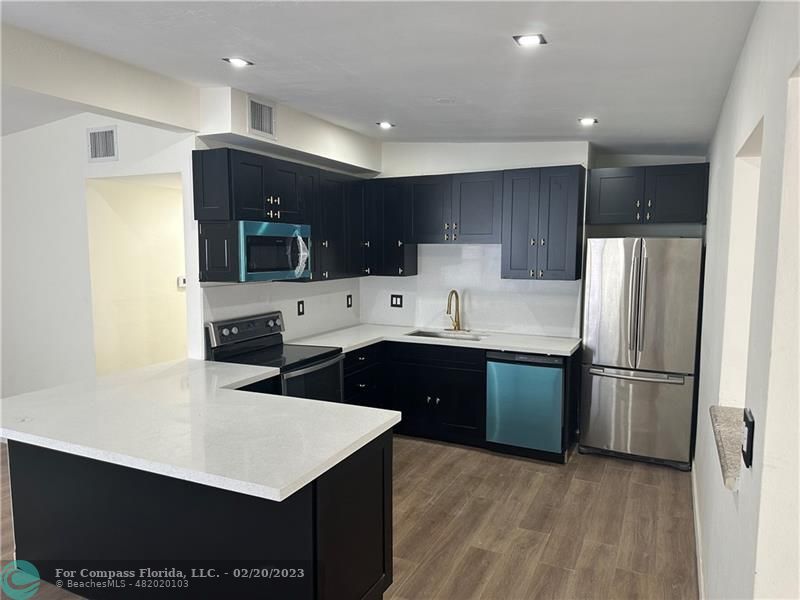 a kitchen with stainless steel appliances a refrigerator a sink a stove a microwave and cabinets