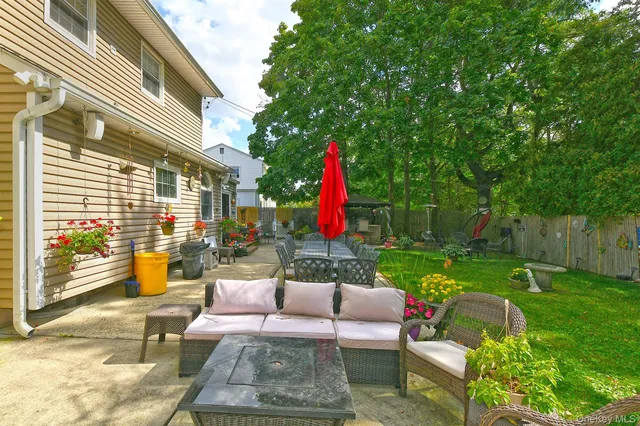a view of a backyard with couches plants and large tree