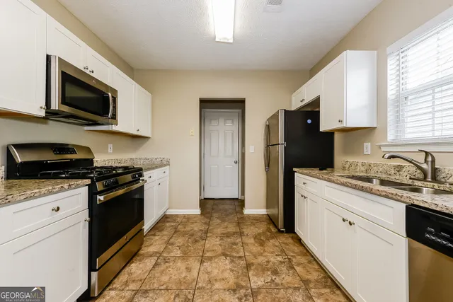 a kitchen with stainless steel appliances granite countertop a stove a sink and a microwave