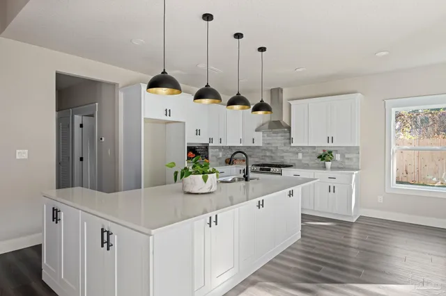 a kitchen with kitchen island granite countertop a stove a sink a counter space and cabinets