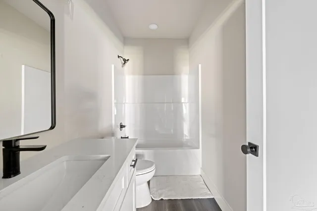 a bathroom with a granite countertop sink toilet a mirror and shower