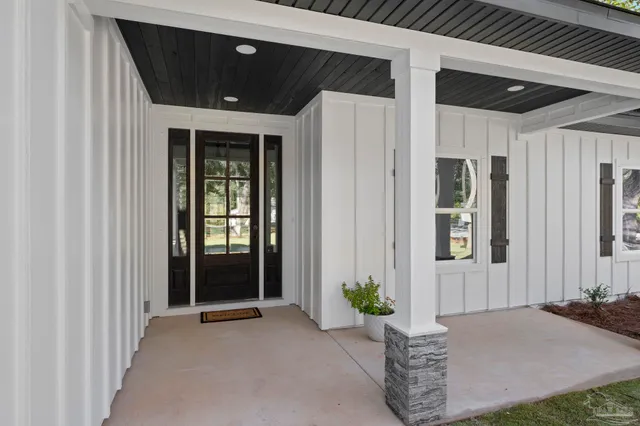 a view of a livingroom with wooden floor a ceiling fan and windows