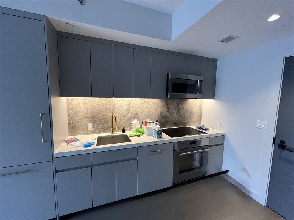 55 Lagrange Street, Unit 1108 Boston, MA 02116 - Photo 10 of 33 a kitchen with stainless steel appliances kitchen island granite countertop a sink and a stove top oven