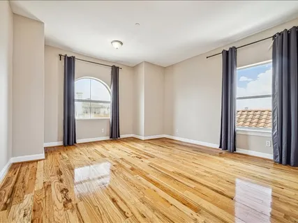 a view of a bedroom with wooden floor and windows