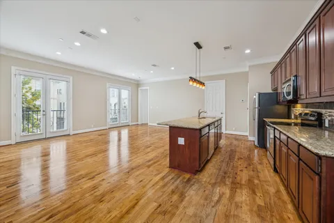 a large kitchen with stainless steel appliances granite countertop a large stove a sink dishwasher a microwave oven and a dining table with wooden floor