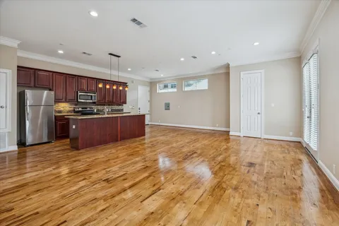a view of kitchen with stainless steel appliances wooden floor and large window