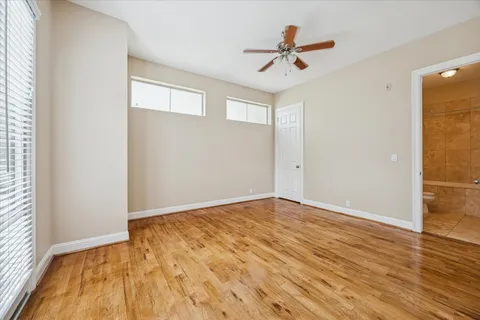 an empty room with wooden floor and ceiling fan