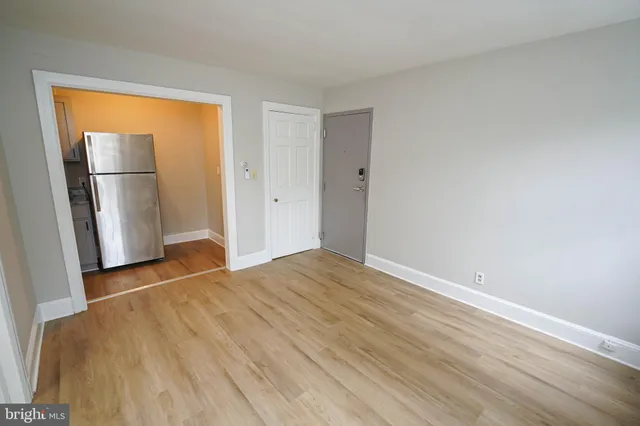 a view of empty room with wooden floor and refrigerator