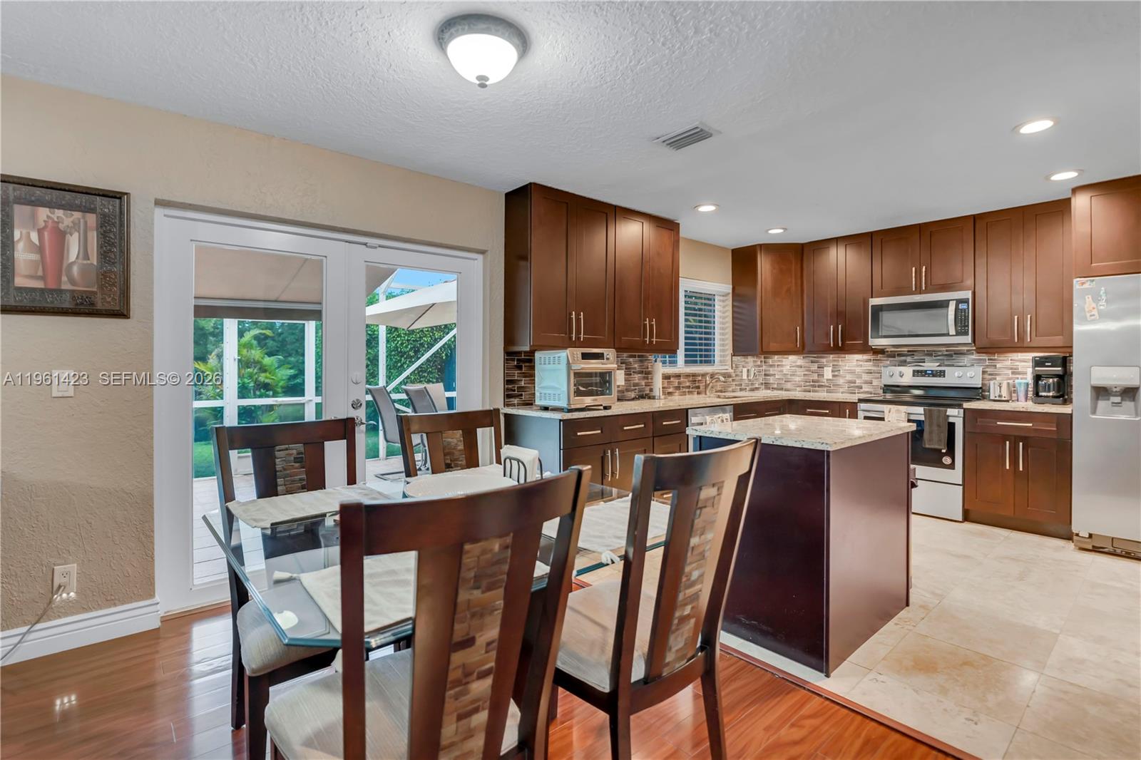 21451 Sawmill Court Boca Raton, FL 33498 - Photo 12 of 67 a kitchen with kitchen island granite countertop wooden floors appliances and furniture