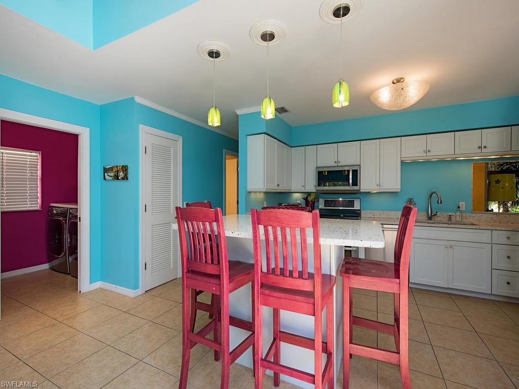 5138 Starfish Avenue Naples, FL 34103 - Photo 6 of 17 a kitchen with stainless steel appliances kitchen island granite countertop a dining table chairs refrigerator and sink