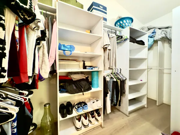 a view of walk in closet with clothes and shoes