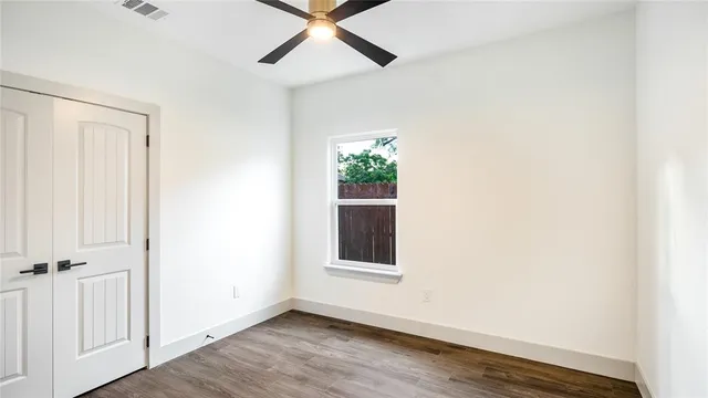 an empty room with wooden floor closet and windows