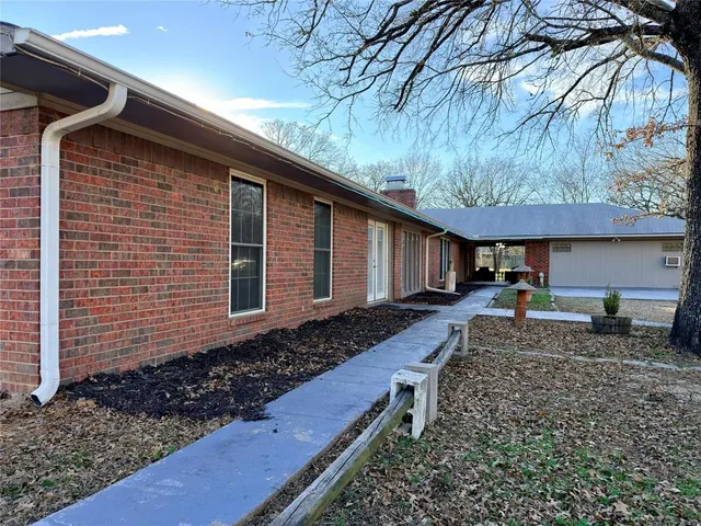 a backyard of a house with large trees and wooden fence