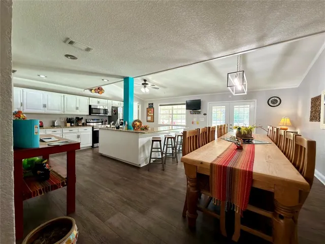 a kitchen with stainless steel appliances a dining table chairs refrigerator and sink