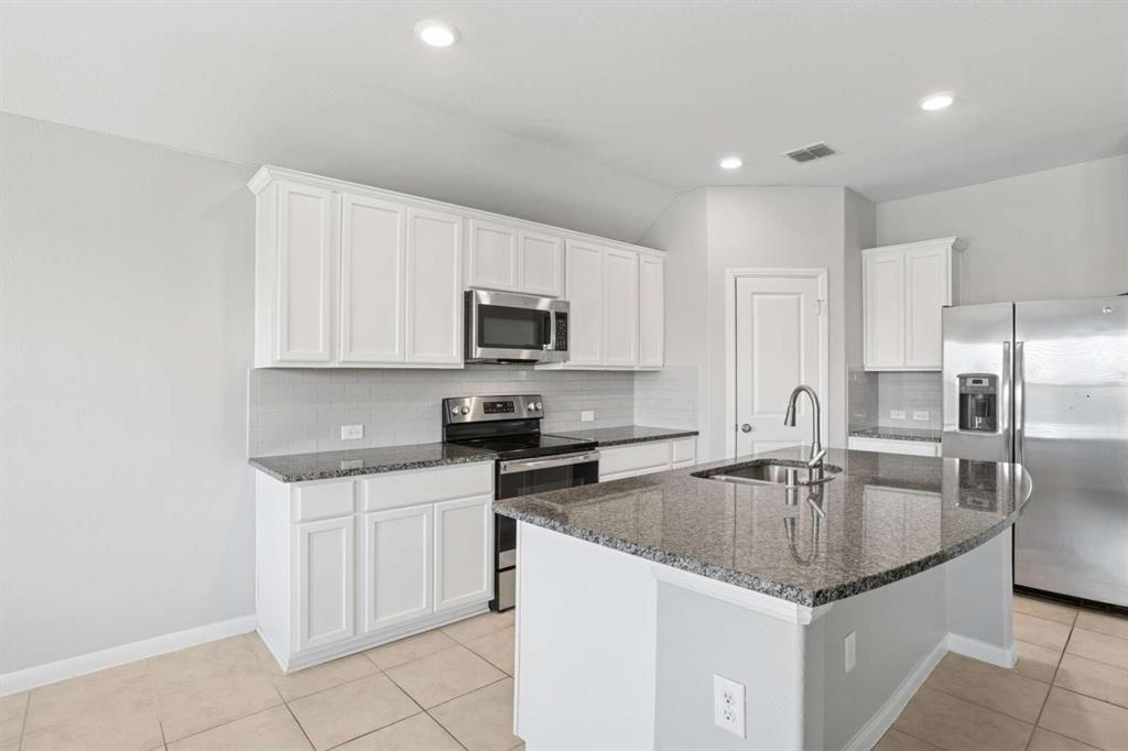 112 Garner Court Forney, TX 75126 - Photo 11 of 15 a kitchen with a sink a microwave a stove and refrigerator