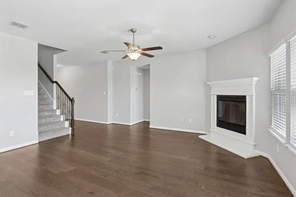 a view of an empty room with wooden floor and a kitchen