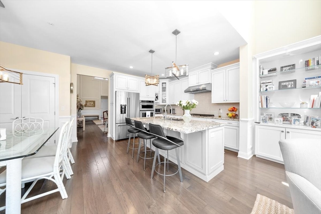 5 Brand Boulevard, Unit 5 Scituate, MA 02066 - Photo 6 of 42 a kitchen with stainless steel appliances kitchen island granite countertop a table chairs and a refrigerator