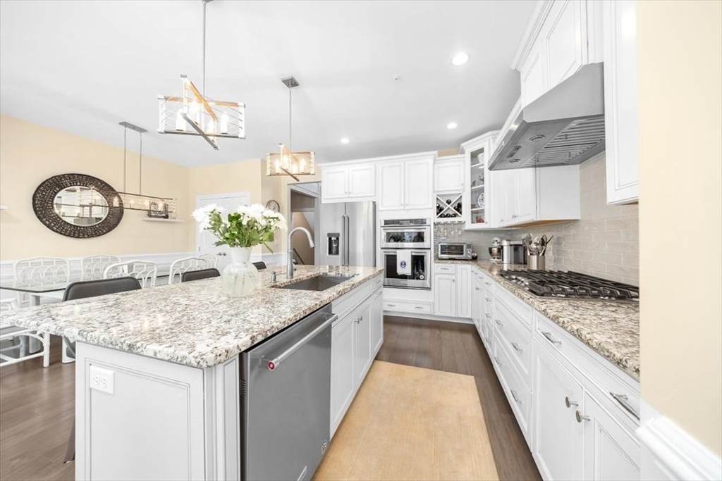 5 Brand Boulevard, Unit 5 Scituate, MA 02066 - Photo 8 of 42 a kitchen with stainless steel appliances granite countertop a sink a stove and a wooden floors