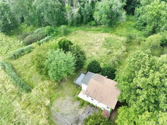 an aerial view of residential house with outdoor space and trees all around