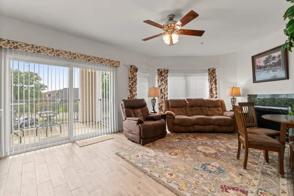 a living room with furniture a ceiling fan and a large window