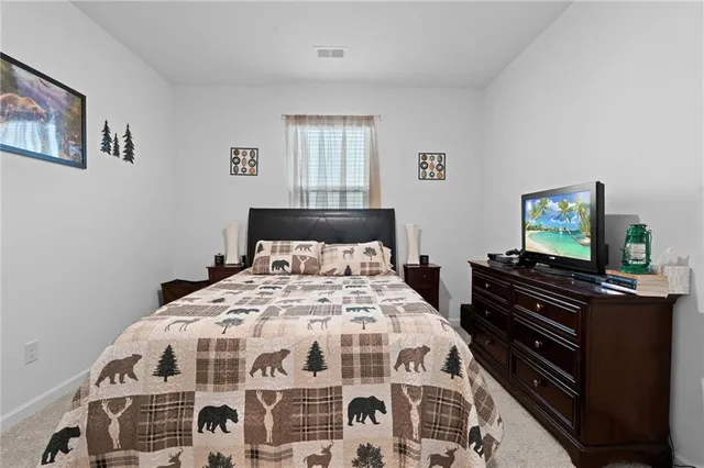 a bedroom with a bed and a flat tv screen on a dresser