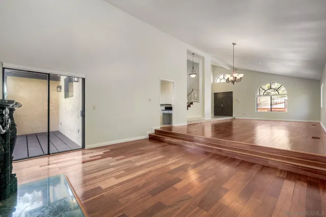 an empty room with wooden floor fireplace and windows
