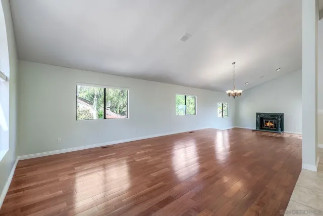 an empty room with windows and fireplace