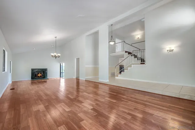an empty room with wooden floor and a fireplace