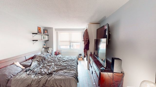 a bedroom with a bed and a flat tv screen on the dresser