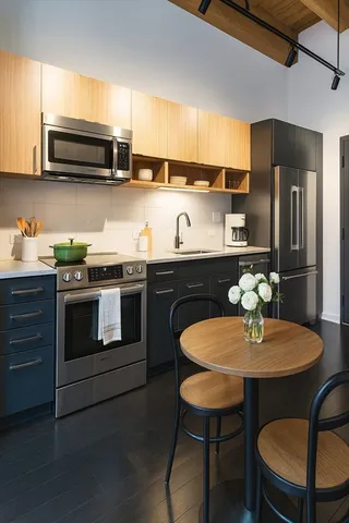 a kitchen with stainless steel appliances a sink a stove a table and chairs