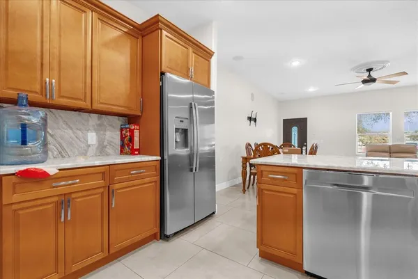 a kitchen with stainless steel appliances granite countertop a refrigerator a sink dishwasher and wooden cabinets with a dishwasher