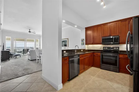 a kitchen with stainless steel appliances granite countertop a refrigerator oven a sink a dining table and chairs